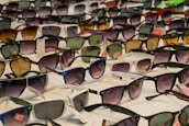A neatly arranged collection of various boys' sunglasses on a white background.