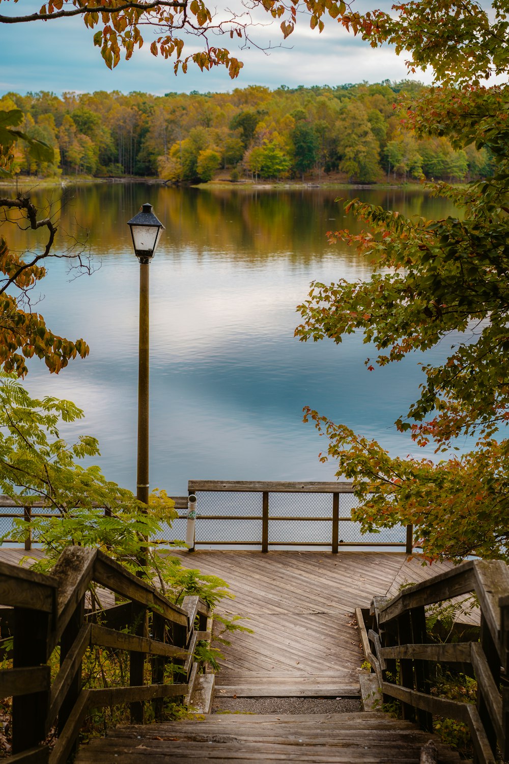 lamp post and wooden deck beside body of water