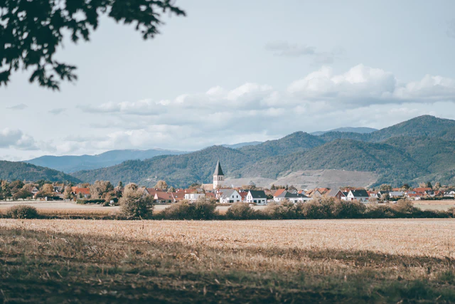 A French village and church bell tower in Alsace between fields and mountains