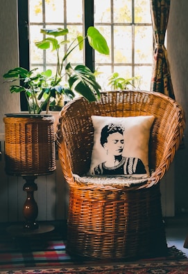 A sunlit corner featuring a rattan chair, macramé wall hanging, and lush green plants.