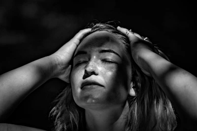 grayscale photography of woman holding her head