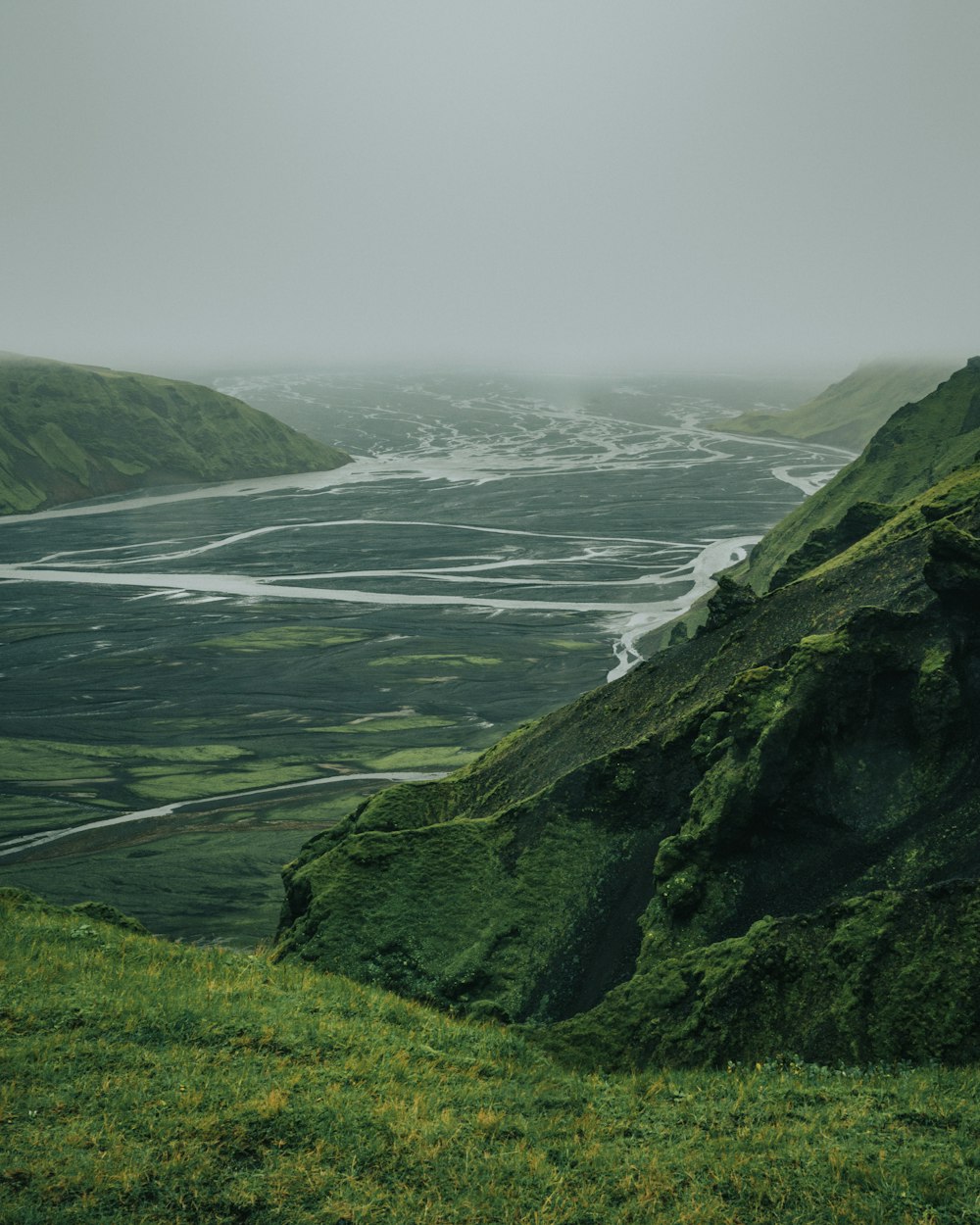 aerial photography of green field viewing mountain and body of water during daytime