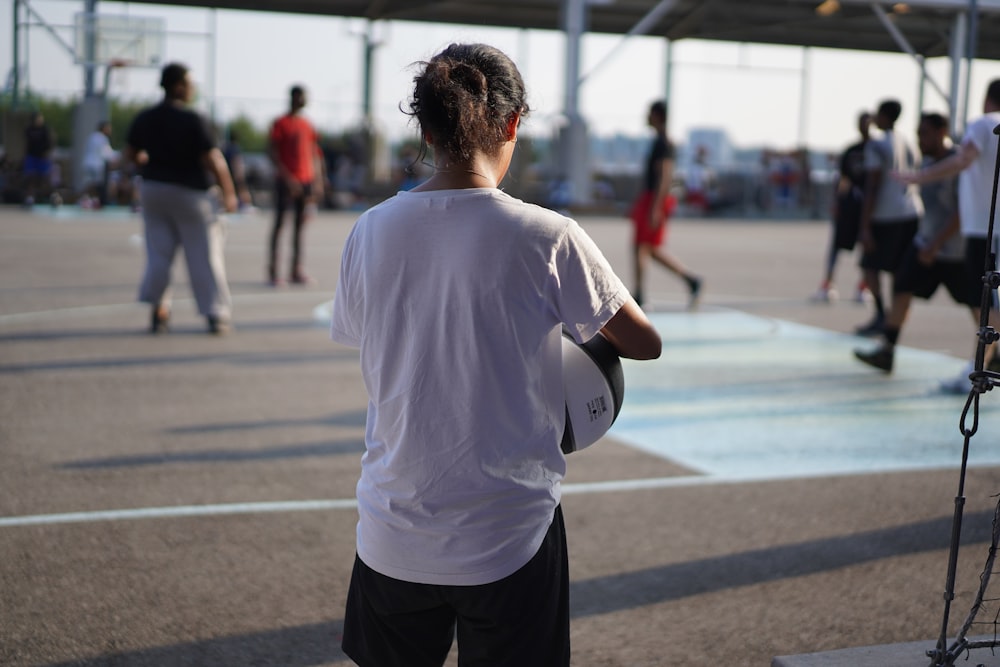 Persona con camiseta blanca de pie cerca de la gente durante el día