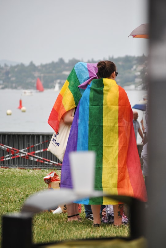 two girls with rainbow flag on back during daytime in Geneva Switzerland