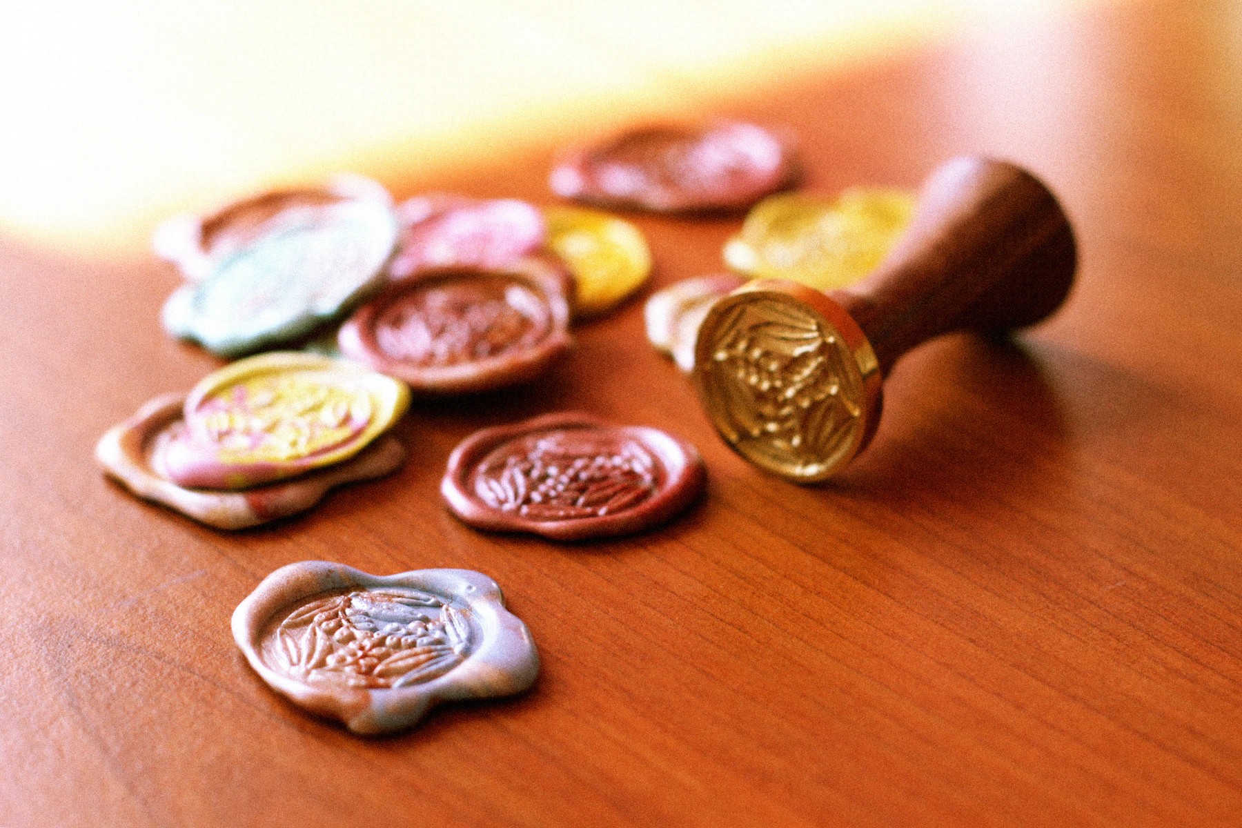 Loose wax seals in mixed colors scattered beside a brass stamp