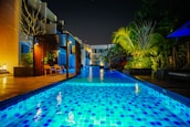 Outdoor pool area with smart lighting and automated irrigation system at dusk.