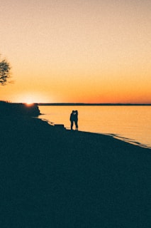 A couple enjoying a sunset on the beach, creating a romantic atmosphere.