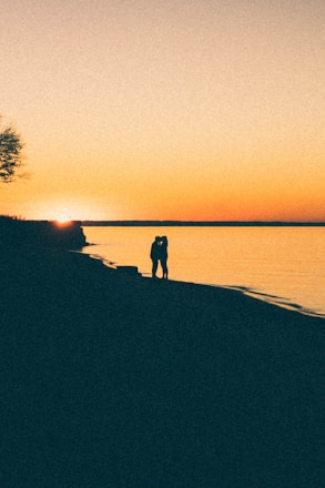A couple enjoying a sunset on the beach, creating a romantic atmosphere.