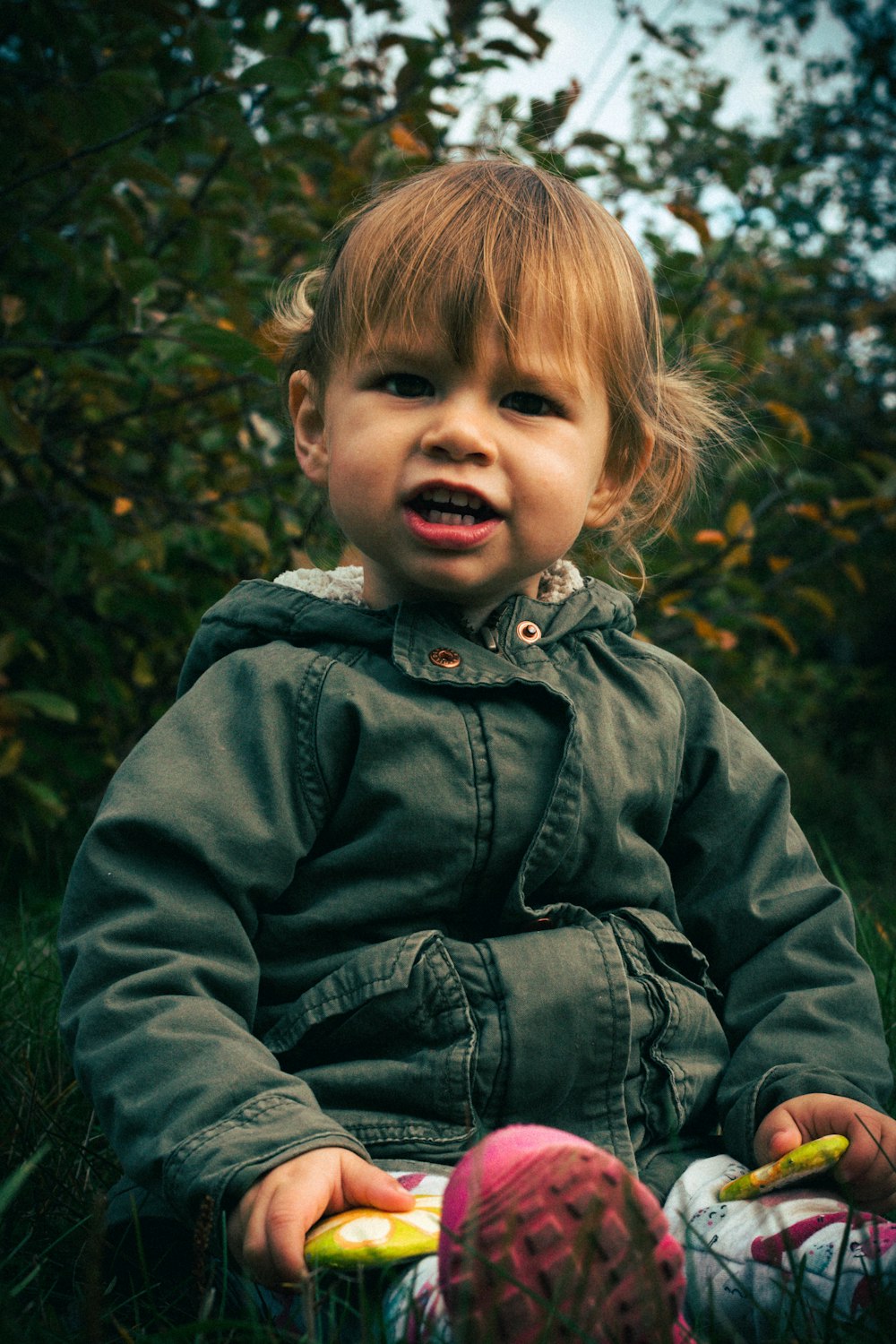 girl wearing blue zip-up jacket sitting on grass