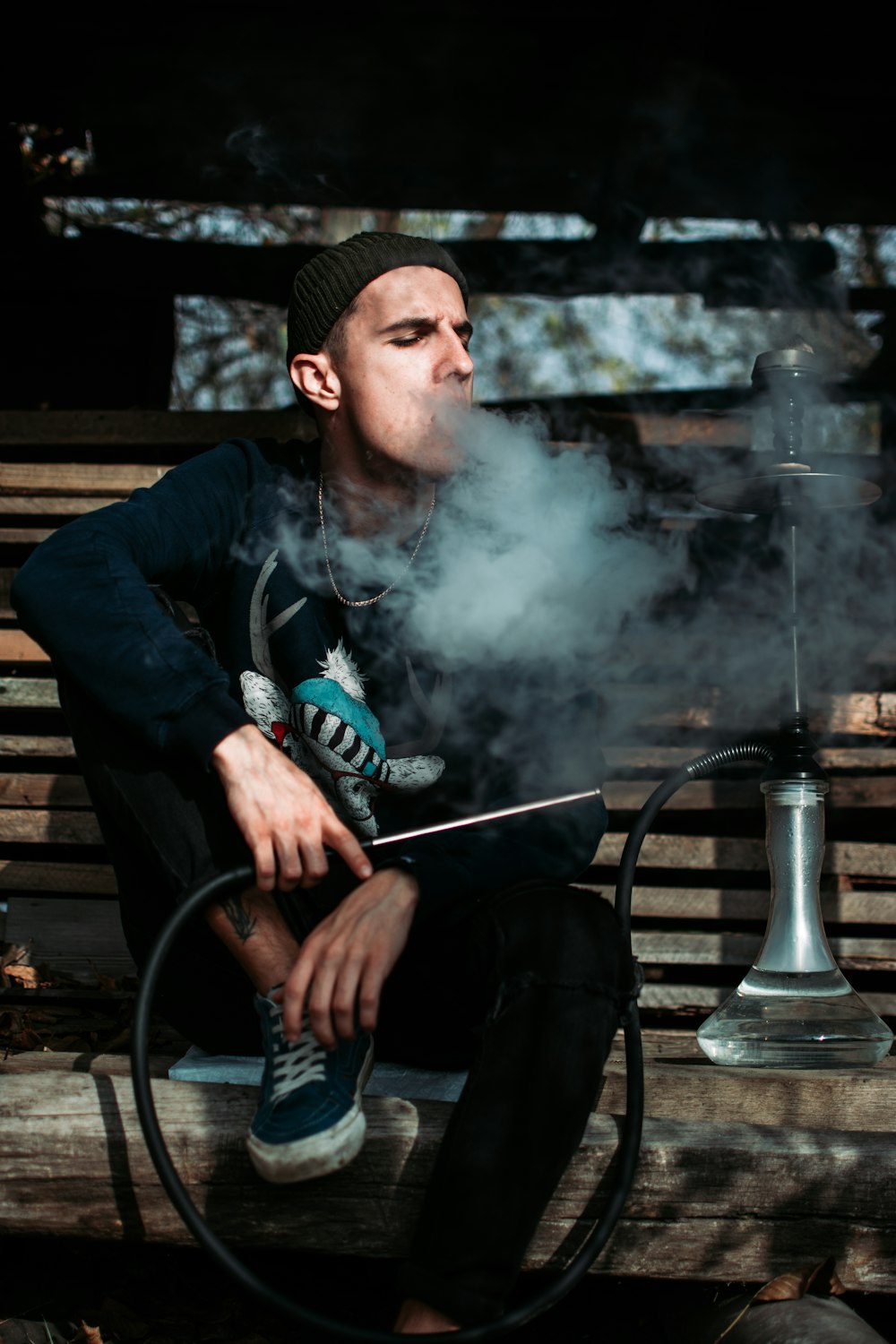 屋外で喫煙する茶色のベンチに座っている男