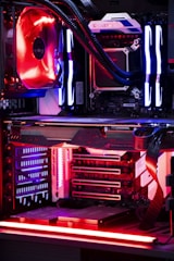 An internal view of a computer showing components like a graphics card, cooling system, and LED lighting. The setup features vibrant red and blue LED lights and a structured, high-tech arrangement with clearly visible branding on the components.