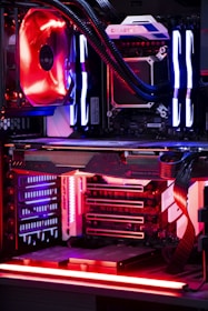 An internal view of a computer showing components like a graphics card, cooling system, and LED lighting. The setup features vibrant red and blue LED lights and a structured, high-tech arrangement with clearly visible branding on the components.