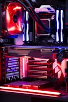 An internal view of a computer showing components like a graphics card, cooling system, and LED lighting. The setup features vibrant red and blue LED lights and a structured, high-tech arrangement with clearly visible branding on the components.