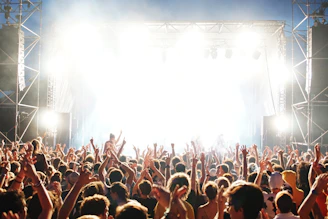 Crowd waving hands under colorful stage lights at a Dubai concert.
