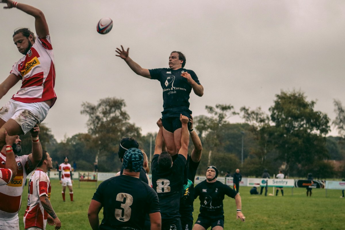 Touche lors d'un match de rugby amateur : un sauteur soulevé par ses coéquipiers tend les bras vers le ballon