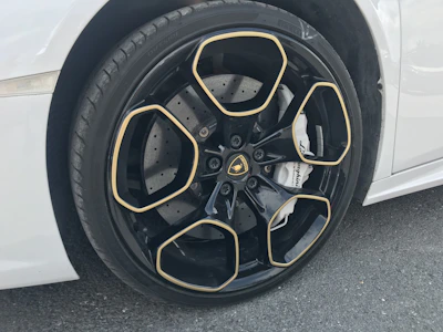 Close-up of glossy black wheel with gold brake calipers shining.