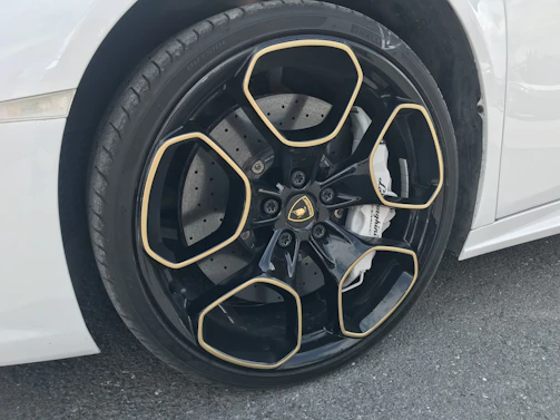 Close-up of a luxury car’s polished wheel and tire, reflecting the yellow and black brand colors.