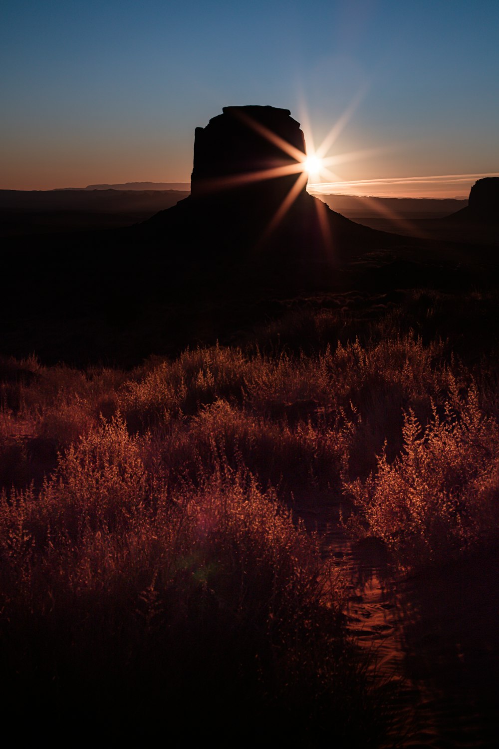 the sun is setting over a mountain in the desert