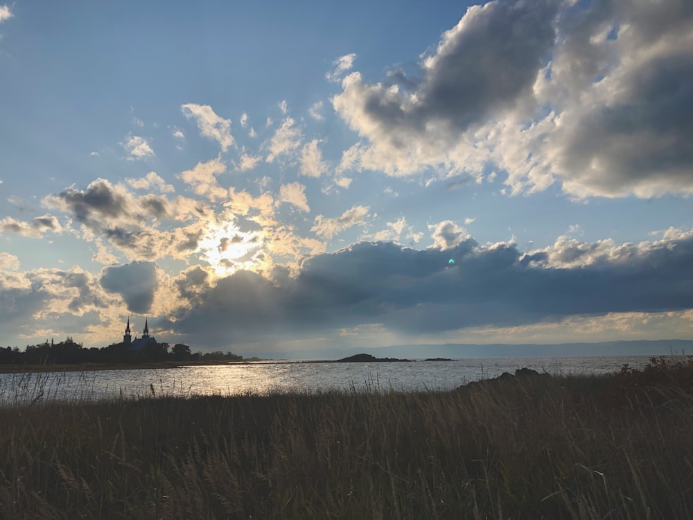 body of water under clouds and blue sky