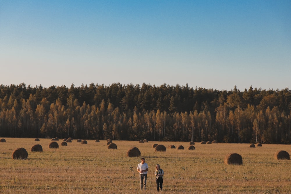 two persons walking on brown field