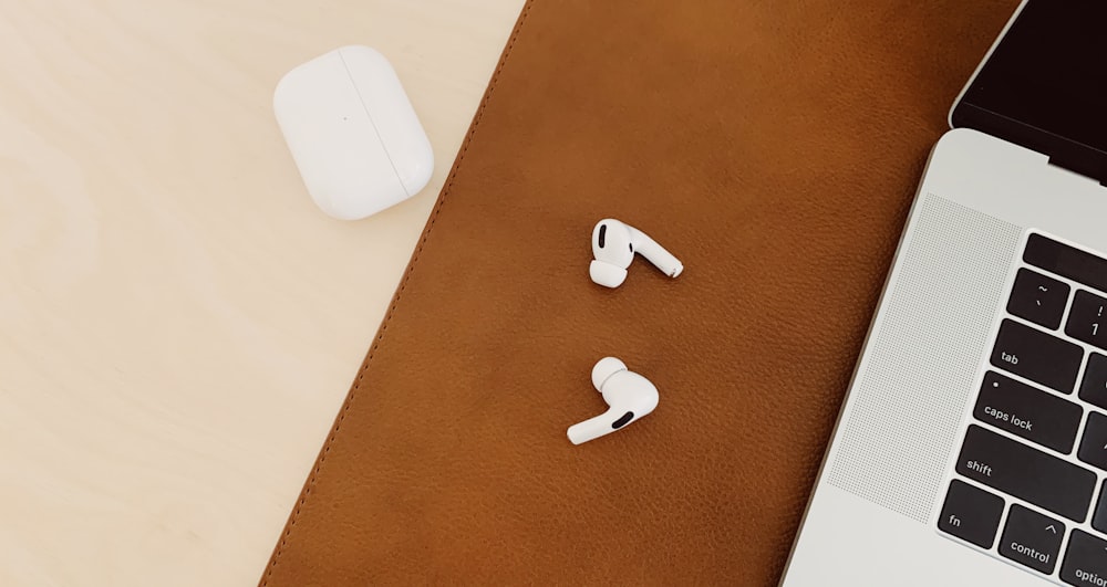 white wireless earbuds beside silver laptop