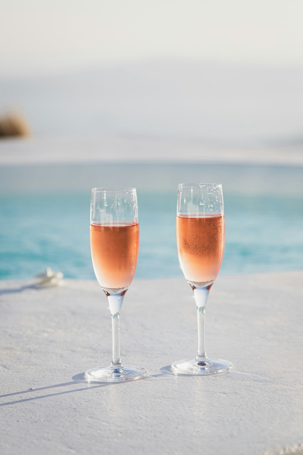 two clear flute glasses on white pavement