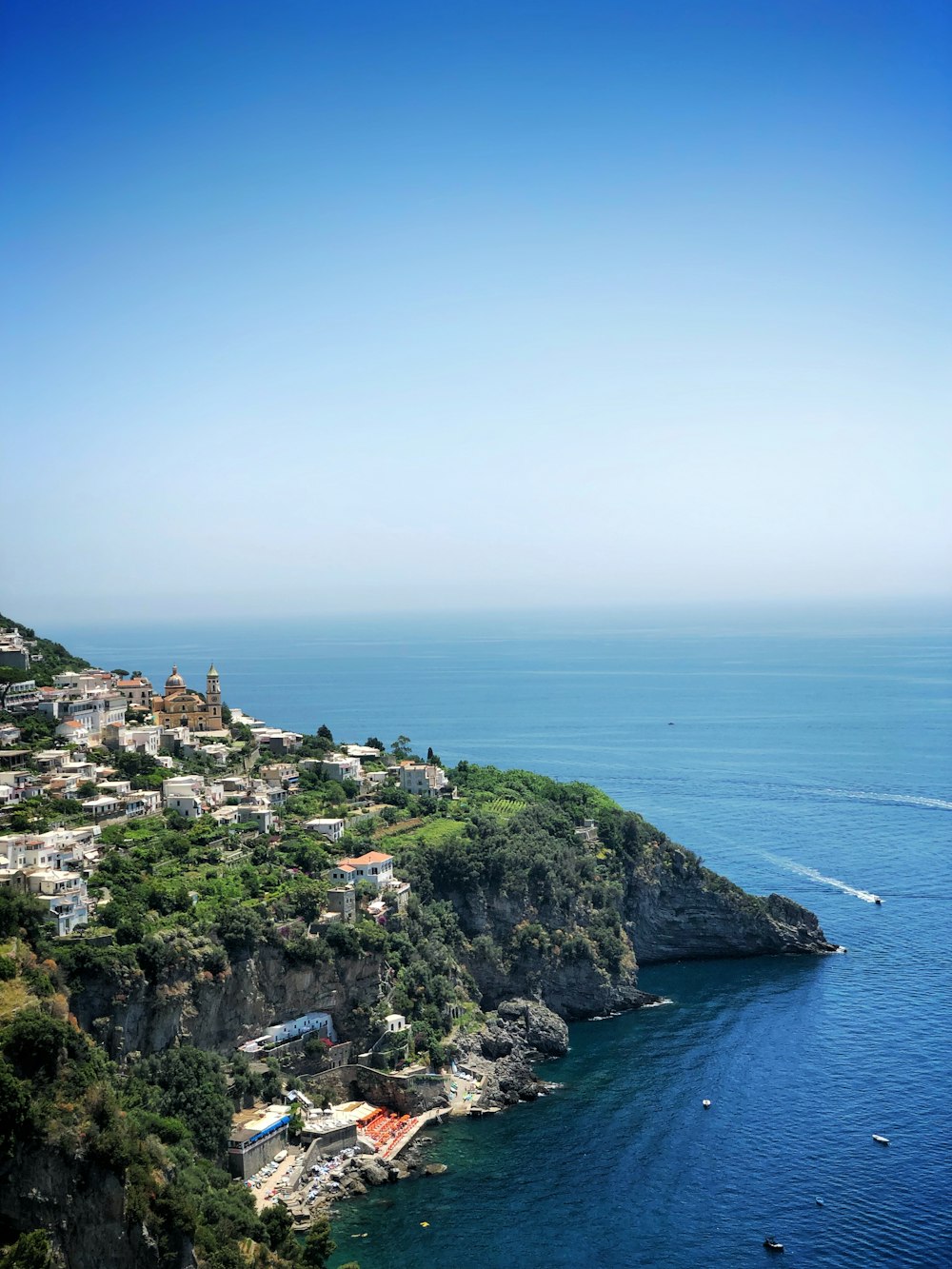 Edifici in cemento bianco sulla scogliera del mare sotto il cielo blu chiaro durante il giorno