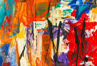 A vibrant abstract painting with bold reds, blues, and yellows blending energetically.