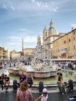 people walking and sitting near water fountain during daytime