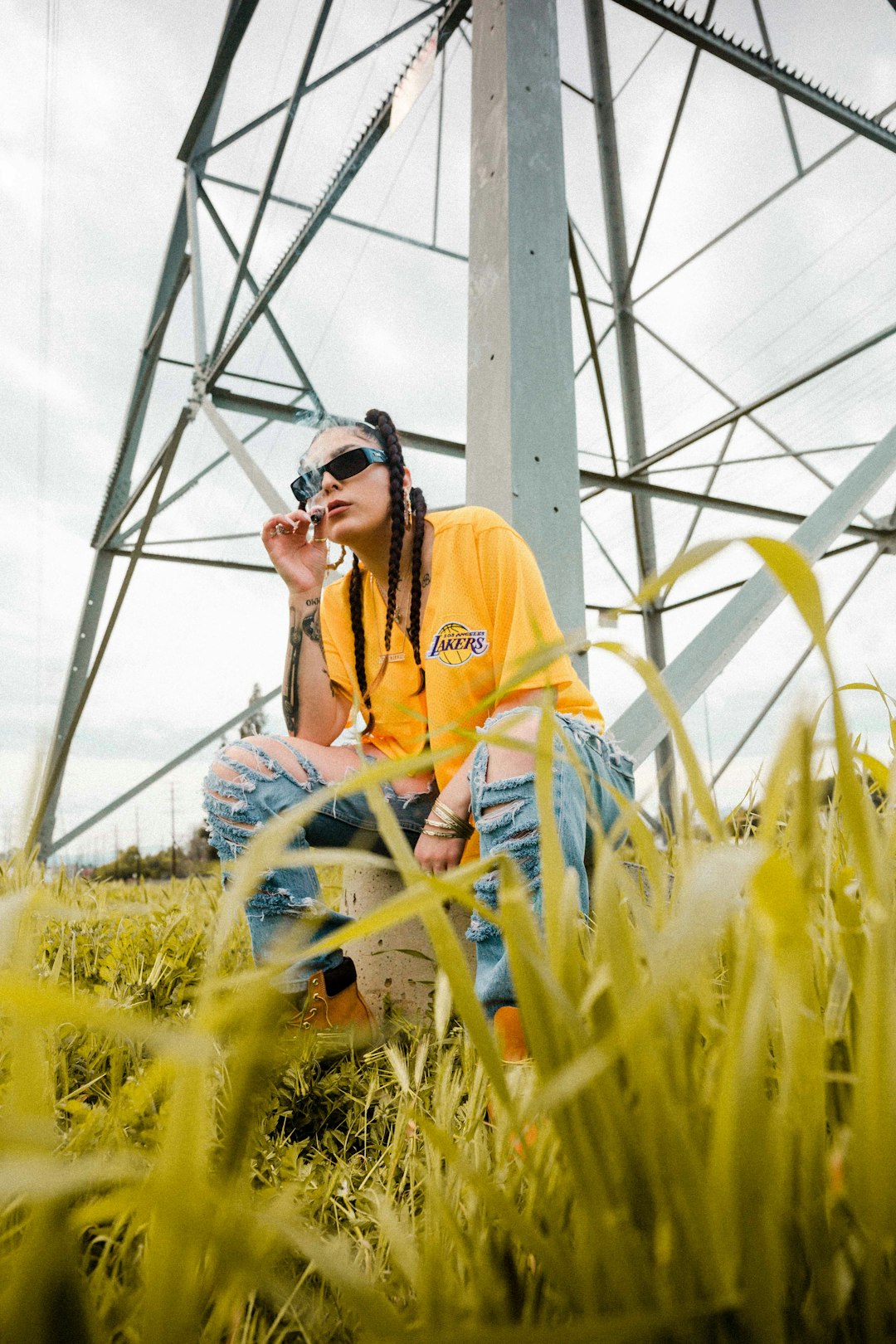 selective focus photography of woman wearing yellow shirt sitting beside transmission tower