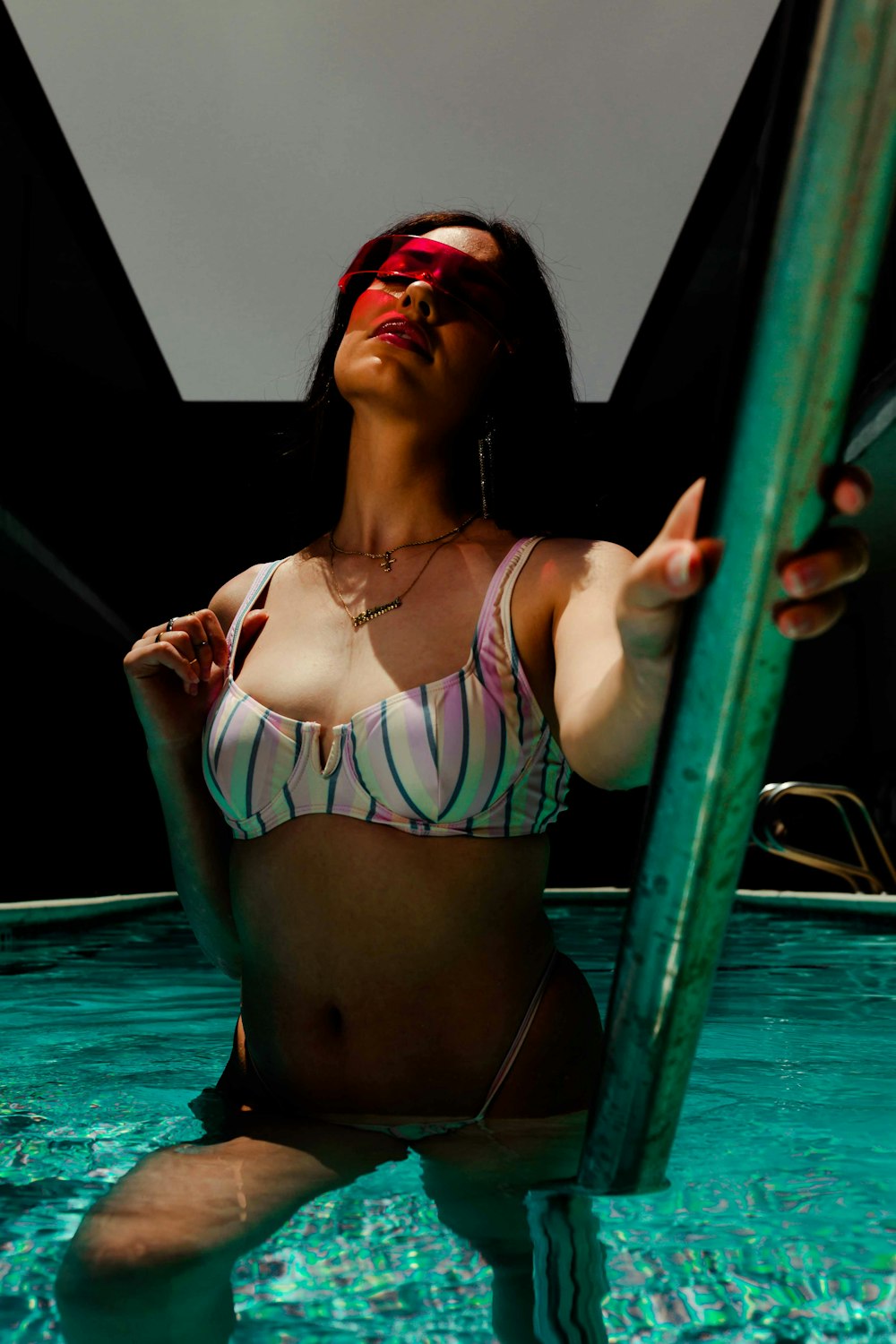 woman wearing pink and black striped bra on swimming pool