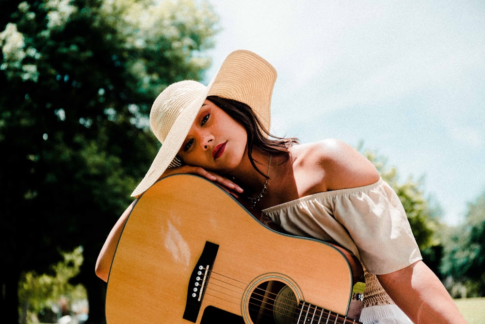 woman wearing white hat holding guitar