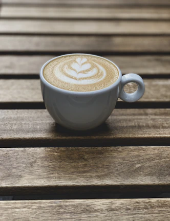 Close-up of a frothy cappuccino with latte art on a rustic wooden table.