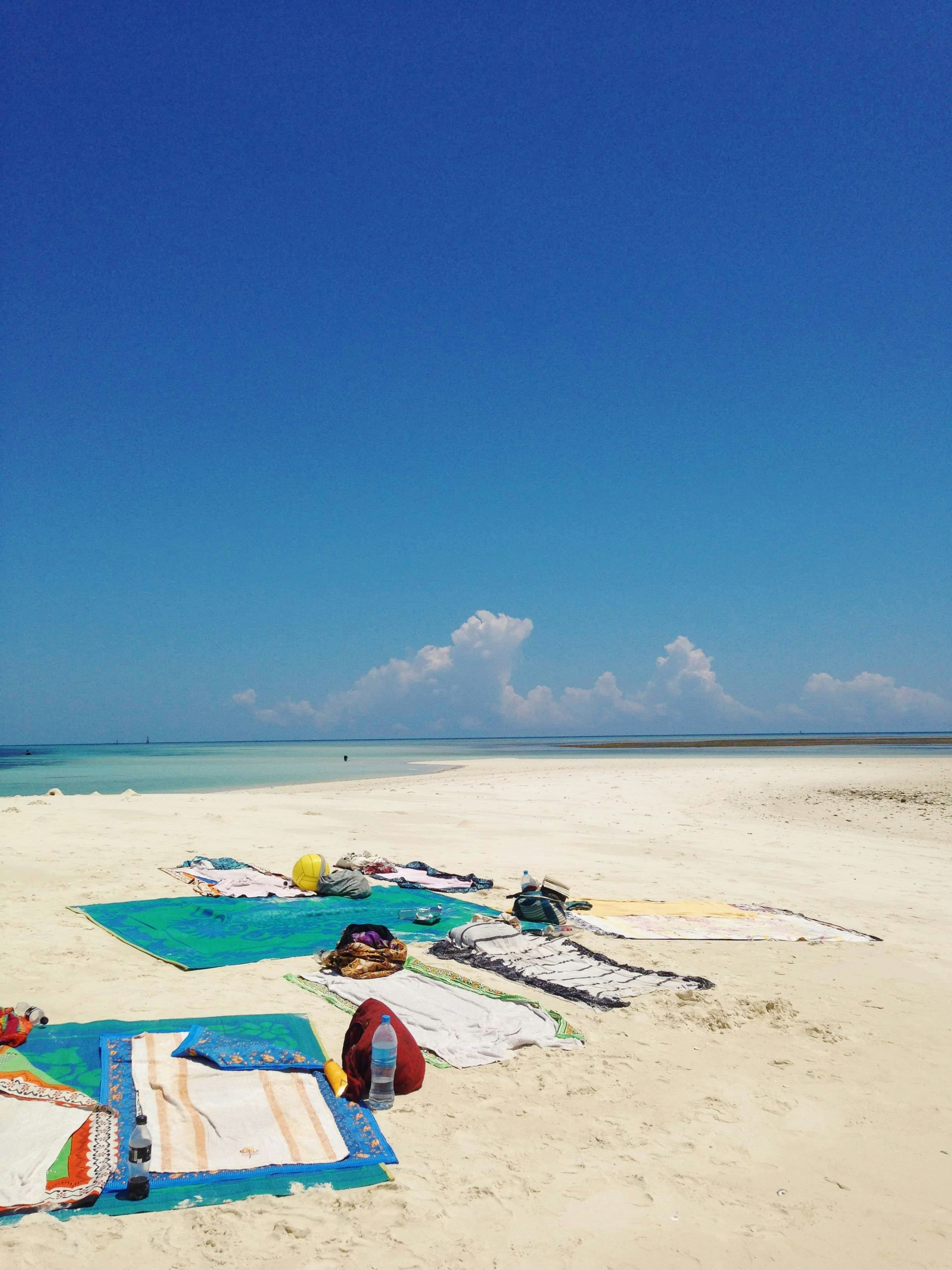 Colorful beach bags and accessories laid on sandy beach, bright sunny Florida day