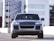 A silver luxury SUV is parked in an urban setting with modern buildings in the background. The vehicle has a sleek and polished exterior with prominent headlights and a distinctive front grille.