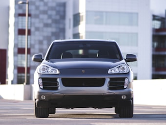 A silver luxury SUV is parked in an urban setting with modern buildings in the background. The vehicle has a sleek and polished exterior with prominent headlights and a distinctive front grille.