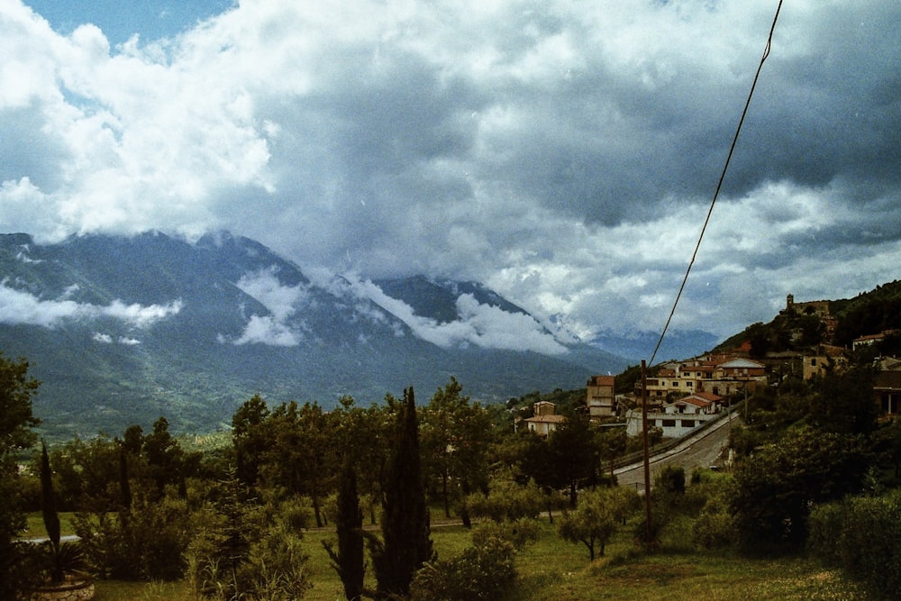 fotografia aerea di case sul campo verde che osserva la montagna sotto il cielo bianco e blu durante il giorno