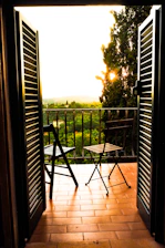 A cozy Italian apartment balcony overlooking a bustling piazza at sunset.