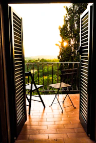 A cozy Italian apartment balcony overlooking a bustling piazza at sunset.