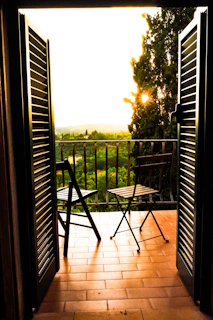 Sunlit balcony with a small table and chairs, perfect for morning tea by the river.