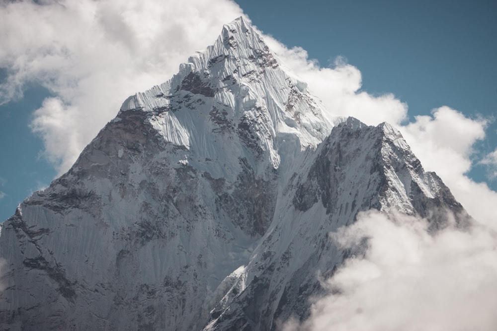 a very tall snow covered mountain in the clouds