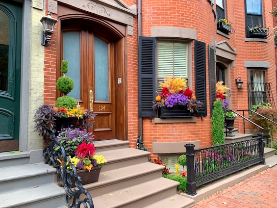 A charming renovated townhouse with a bright red door and flower boxes under the windows.