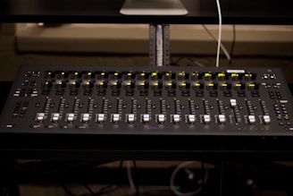 A professional sound mixing board with hands adjusting levels during post-production