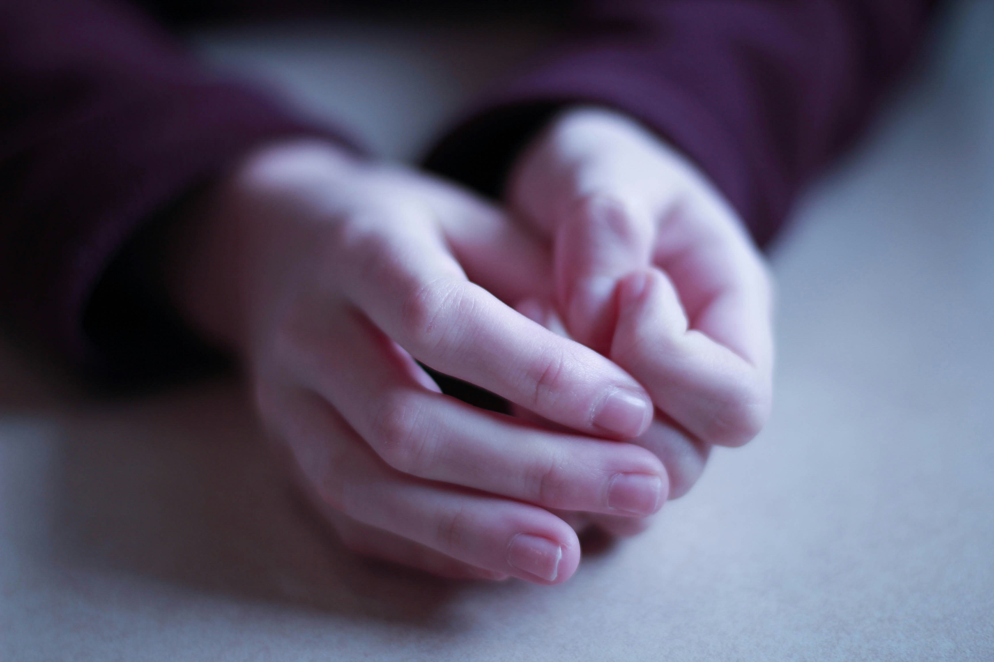 Hands clasped in prayer in soft natural light, peaceful and reverent atmosphere