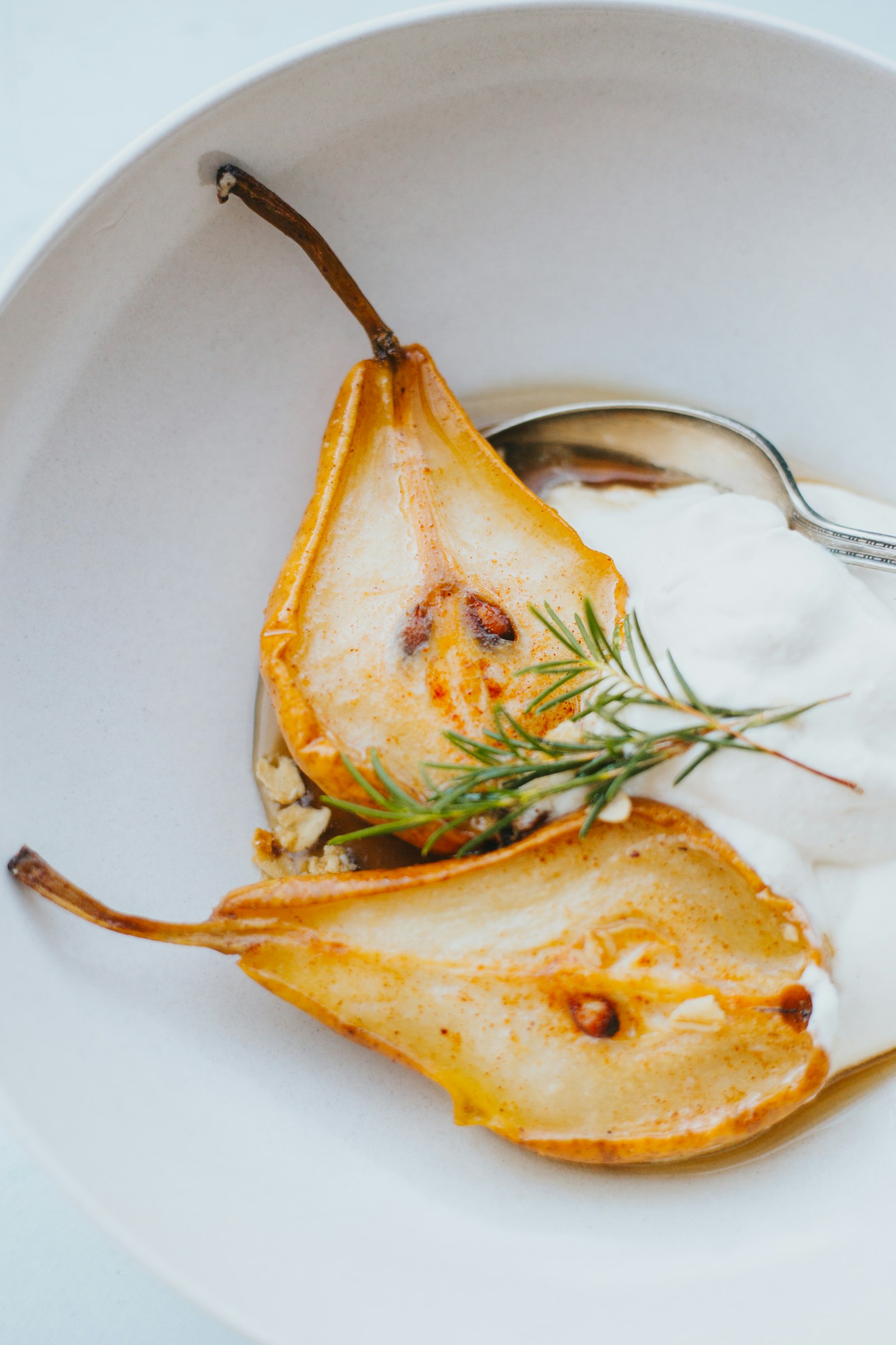 Deux moitiés de poire rôtie dans une assiette blanche