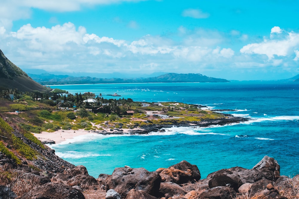 aerial photography of blue sea viewing mountain under white and blue sky during daytime