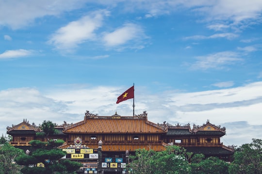 brown buildings with Vietnam flag on roof under blue and white sky during daytime in Hue Vietnam