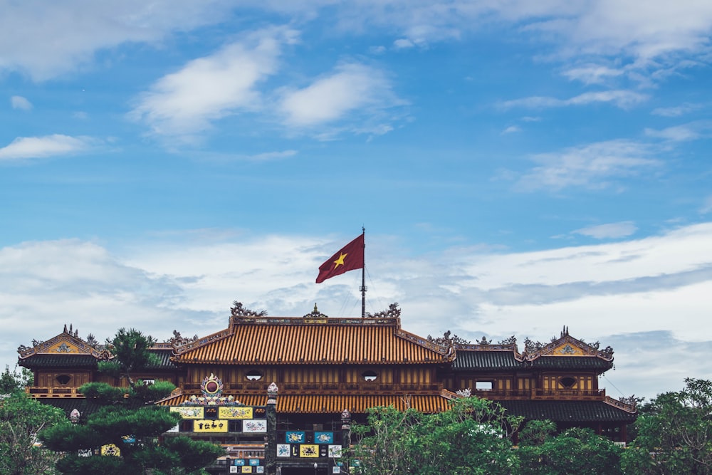 brown buildings with Vietnam flag on roof under blue and white sky during daytime