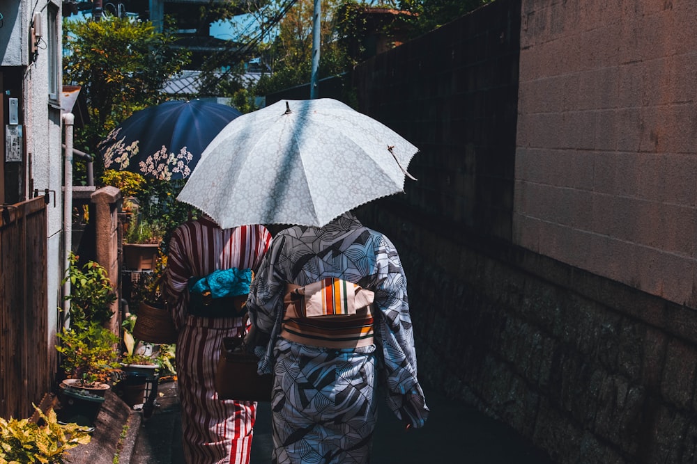 person wearing white and black kimono using umbrella while walking near buildings
