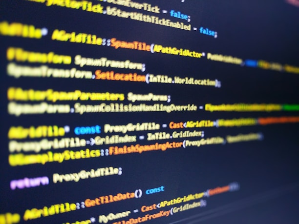 A close-up shot of computer code displayed on a monitor. The code syntax includes keywords and commands typically used in programming, with varying colors like yellow, blue, and white for different elements. The image has a shallow depth of field with the focus on the central portion of the script.